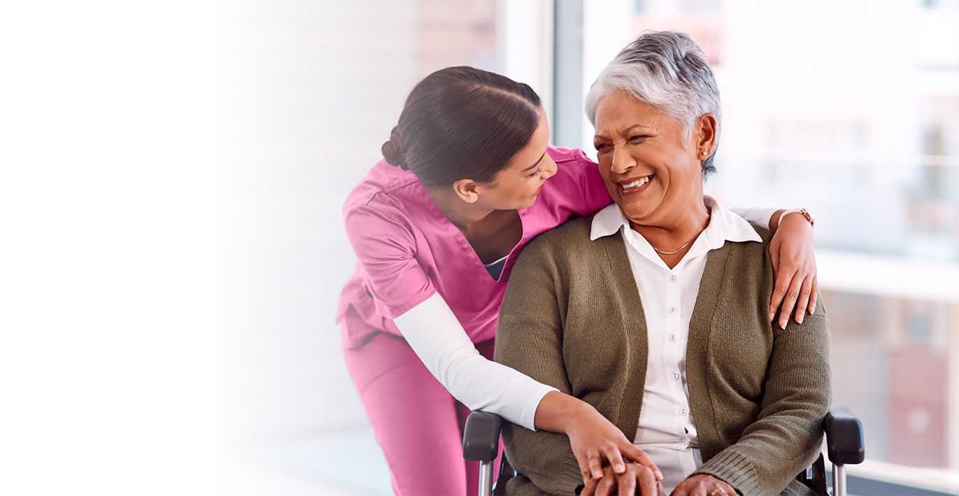 caregiver smiling and senior lady on wheelchair