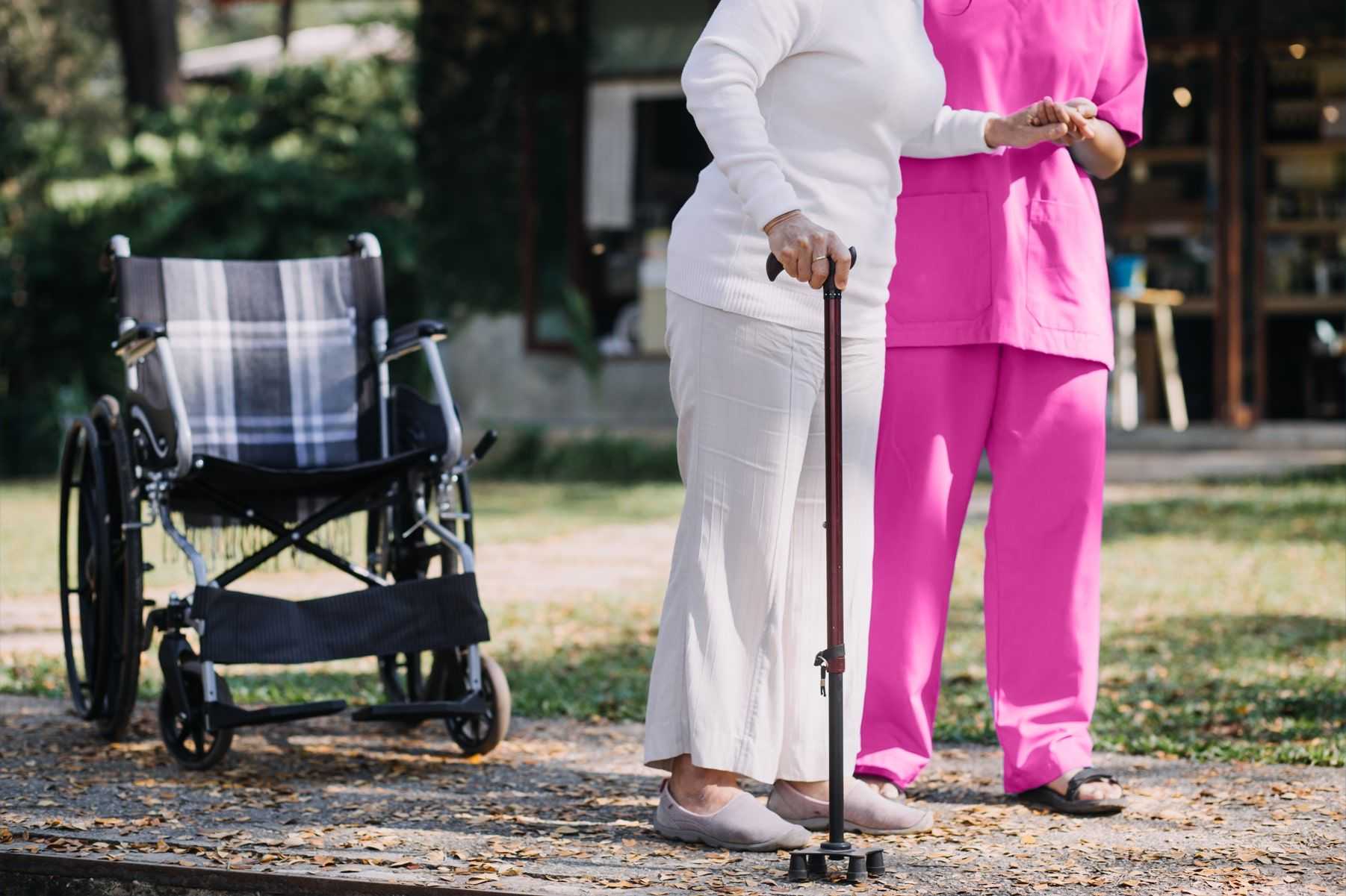 Caregiver helping lady with cane