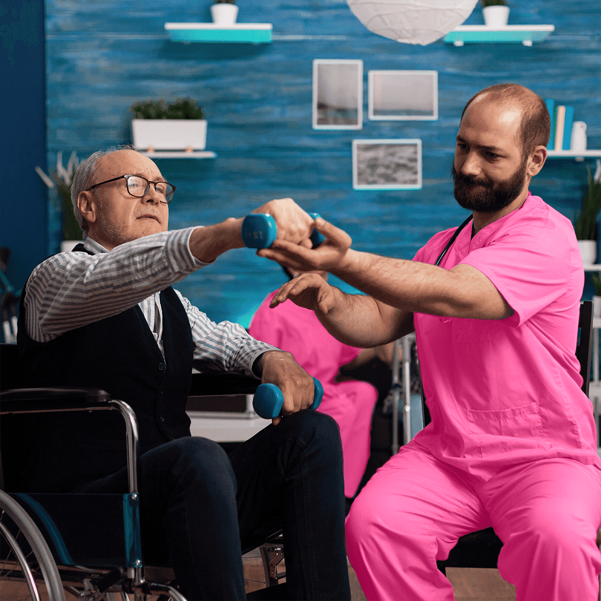 Elder man in wheelchair excercissing with the help of bearded caregiver