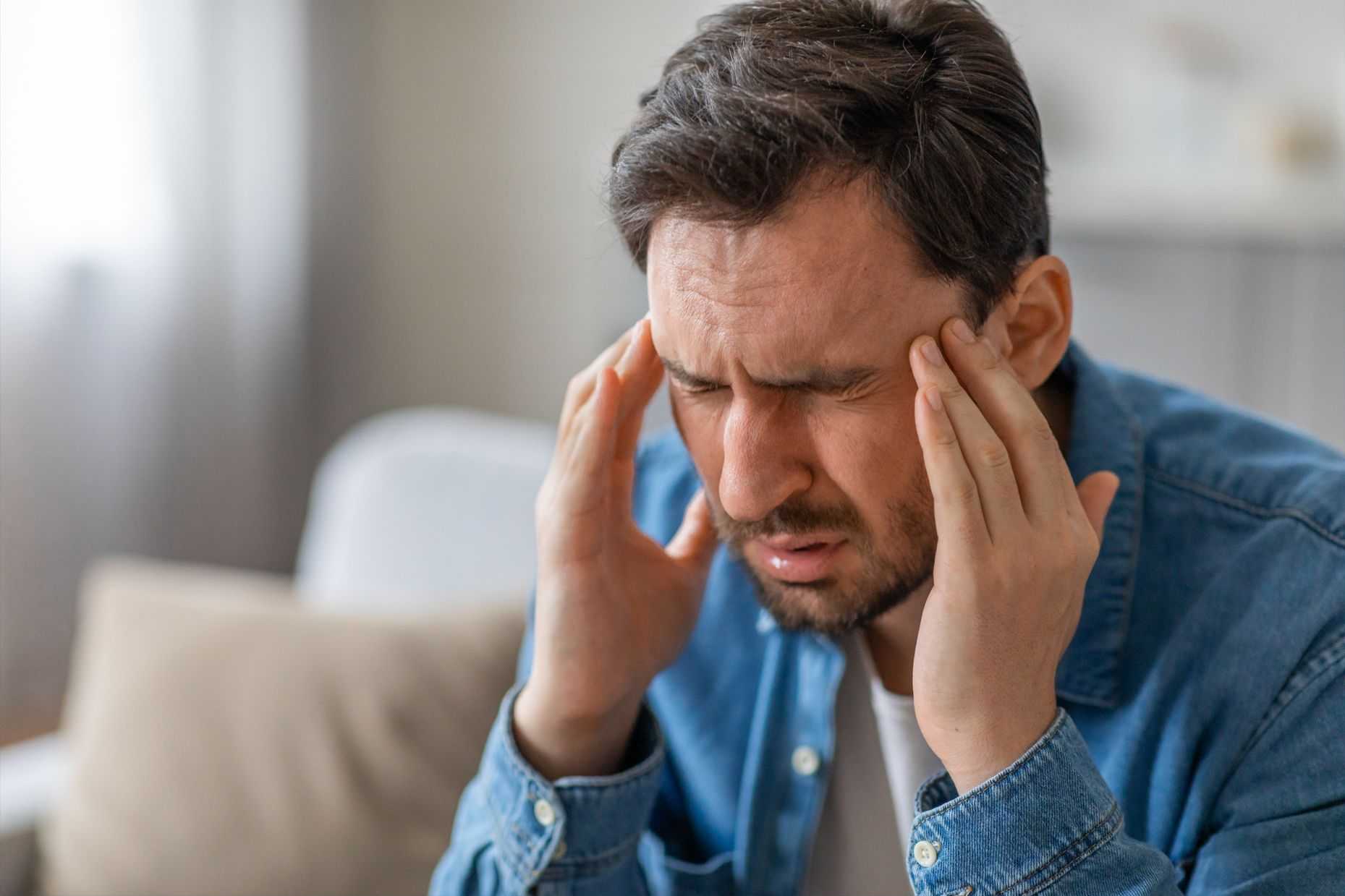 man rubbing sides of head