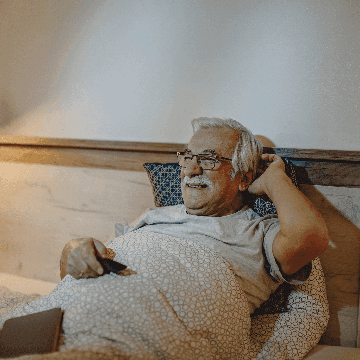 Happy senior man watching tv while relaxing bed