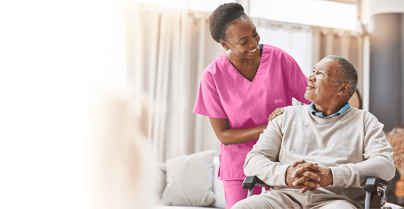 Nurse touching shoulder of senior man on wheelchair