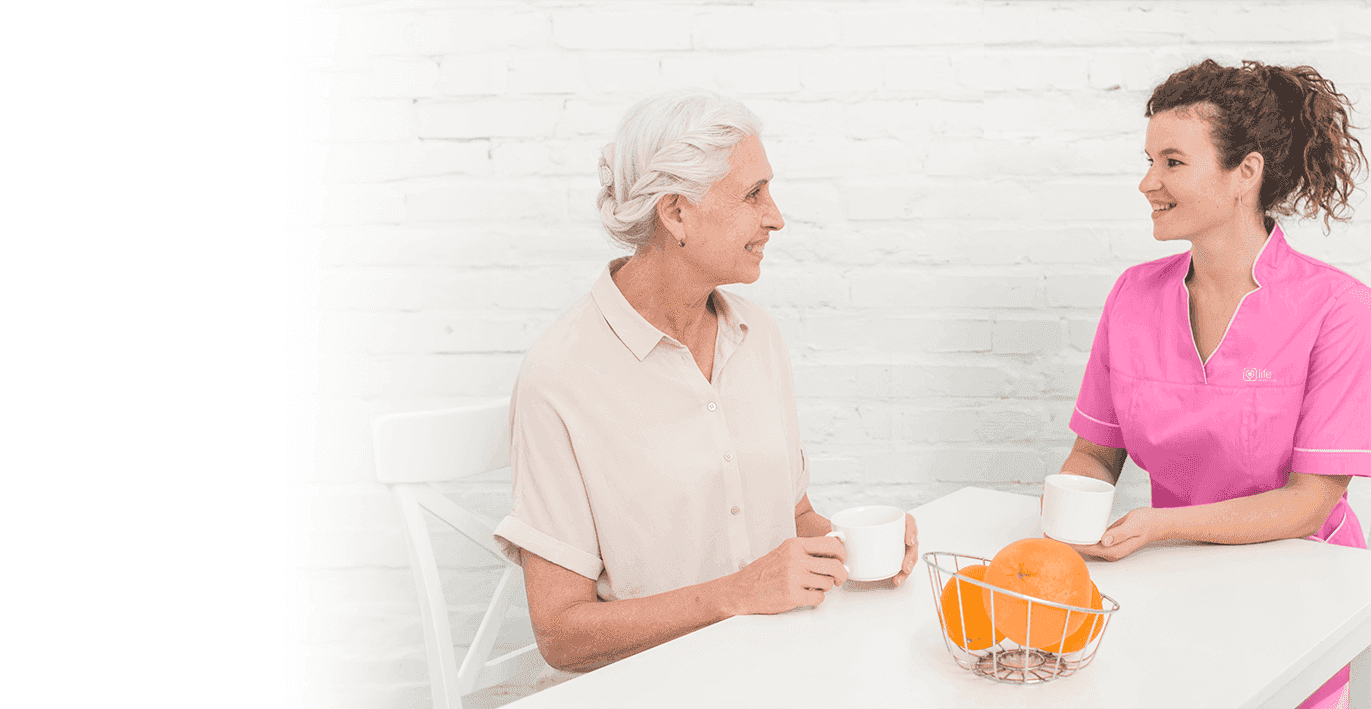 caregiver and elderly woman having tea together