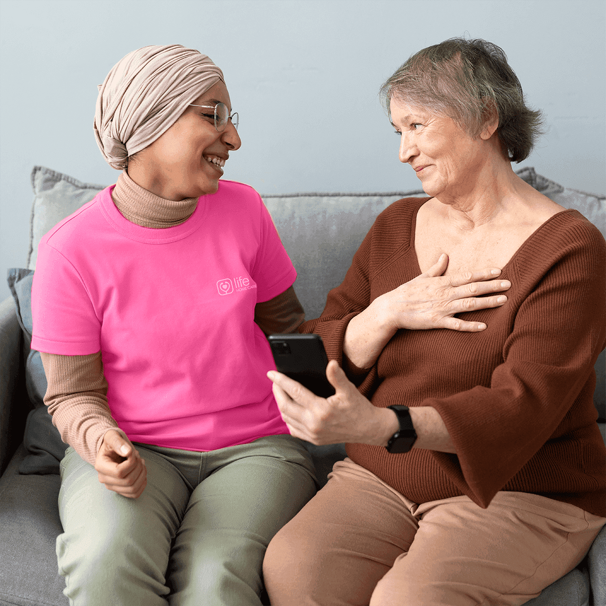 arabic woman is teaching senior woman use smartphone in living room