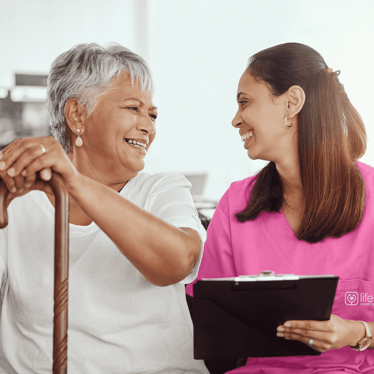 caregiver and elderly woman sitting on couch smiling 