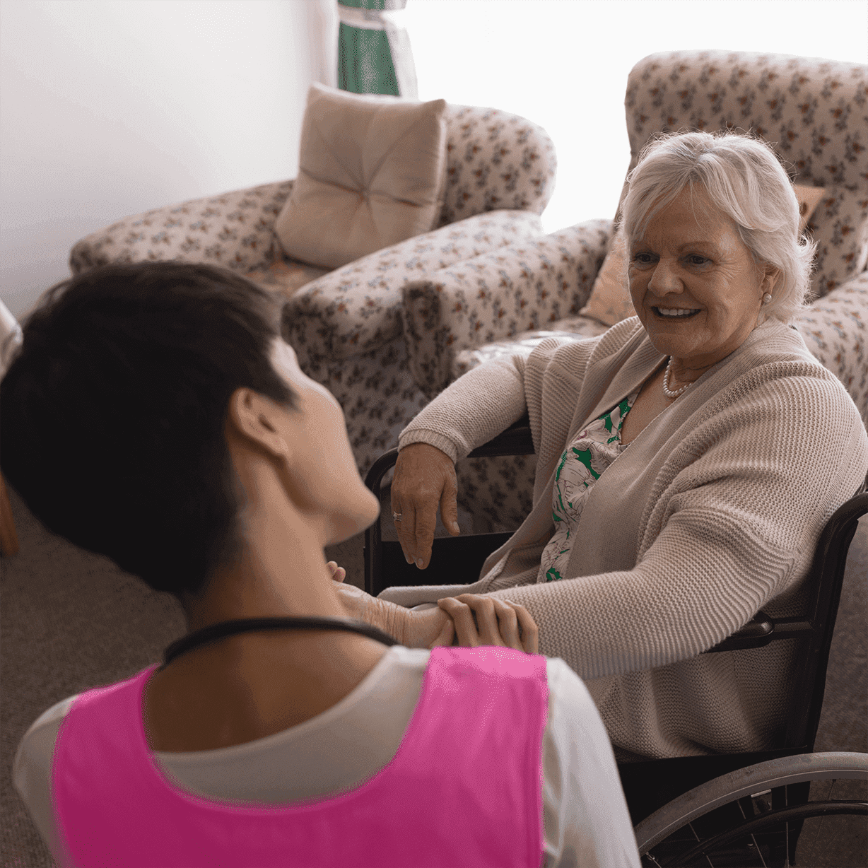 young nurse interacting with senior woman in wheelchair