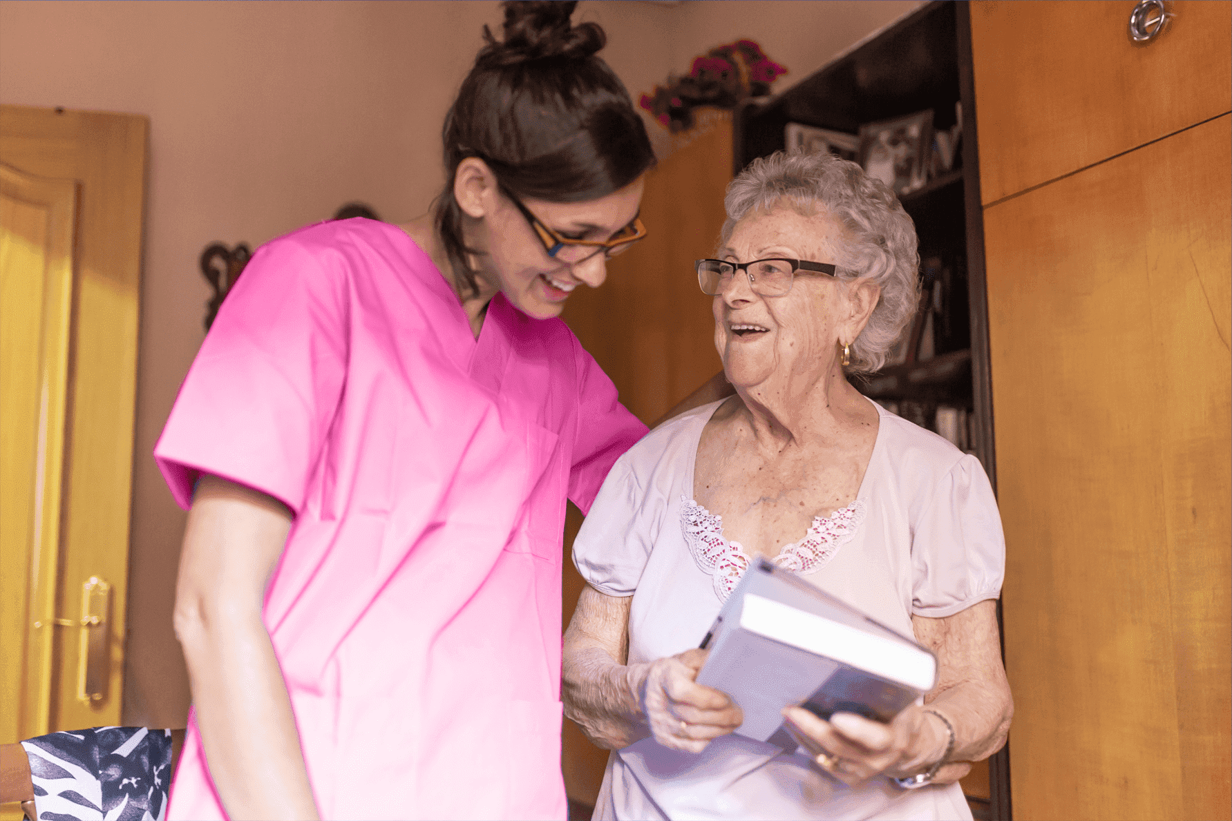 carefiver smiling at senior lady olding book